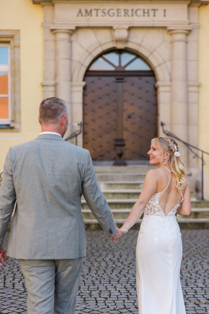 Eine Braut in einem rückenfreien Kleid strahlt ihren Bräutigam an. Eine Braut in einem rückenfreien Kleid strahlt ihren Bräutigam an.